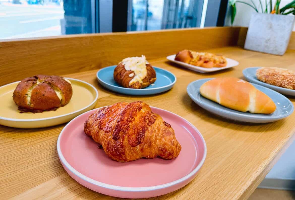 Delicious pastries sit on colourful plates in the window at From Scratch